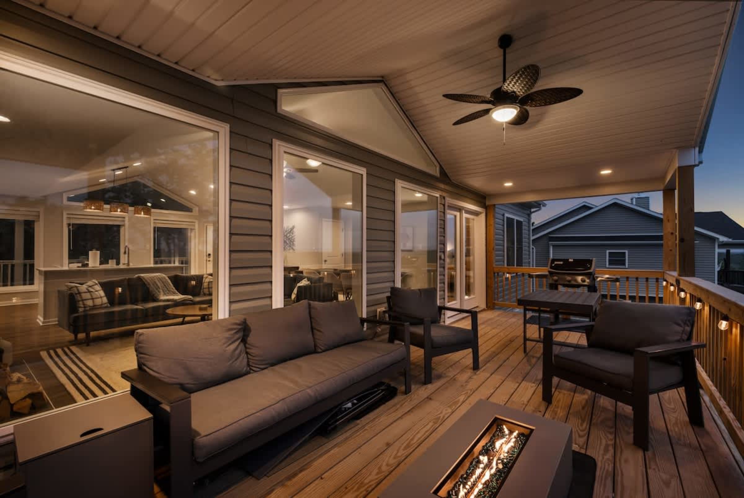 Covered deck at dusk with a fire pit lounge and outdoor dining above the valley